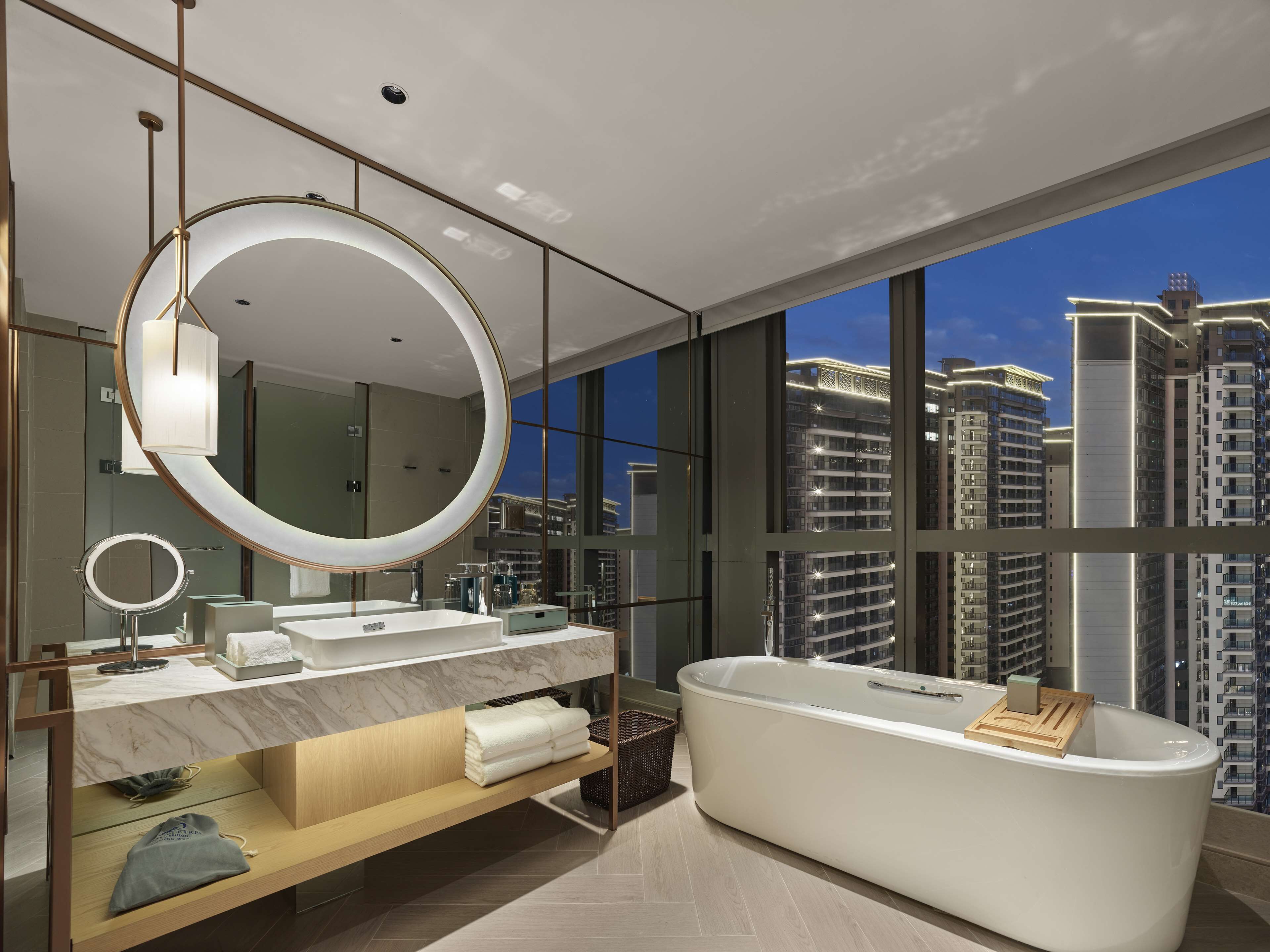 A modern bathroom with a freestanding bathtub, a large mirror, and a vanity with two sinks.