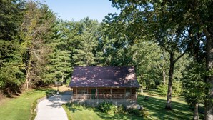 A cabin with a porch, surrounded by trees and a grassy area. - Valentine Drive Cabin 1 (Lookout Mountain)
