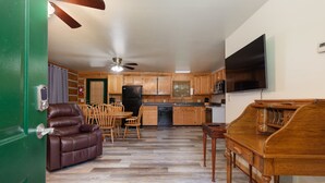 A spacious living area with a brown leather sofa, wooden dining table, and a ceiling fan. - Valentine Drive Cabin 1 (Lookout Mountain)