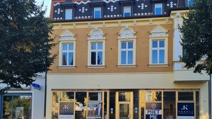 A two-story building with a yellow facade and black roof. There are large windows on the ground floor and decorative elements above the windows. - Apartment Fuchsbau (Senftenberg)