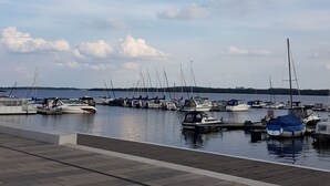 A marina with various boats docked, a clear sky, and a distant shoreline. - Apartment Fuchsbau (Senftenberg)