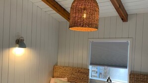 Makuuhuoneessa on kaksi sänkyä, punottu riippuvalaisin, seinään kiinnitetty lamppu ja ikkuna, jossa on sälekaihtimet.