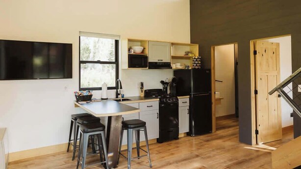 A modern kitchen with a central island, bar stools, and a black refrigerator. - Redoubt cabin @ Keystone Kozy (Soldotna)