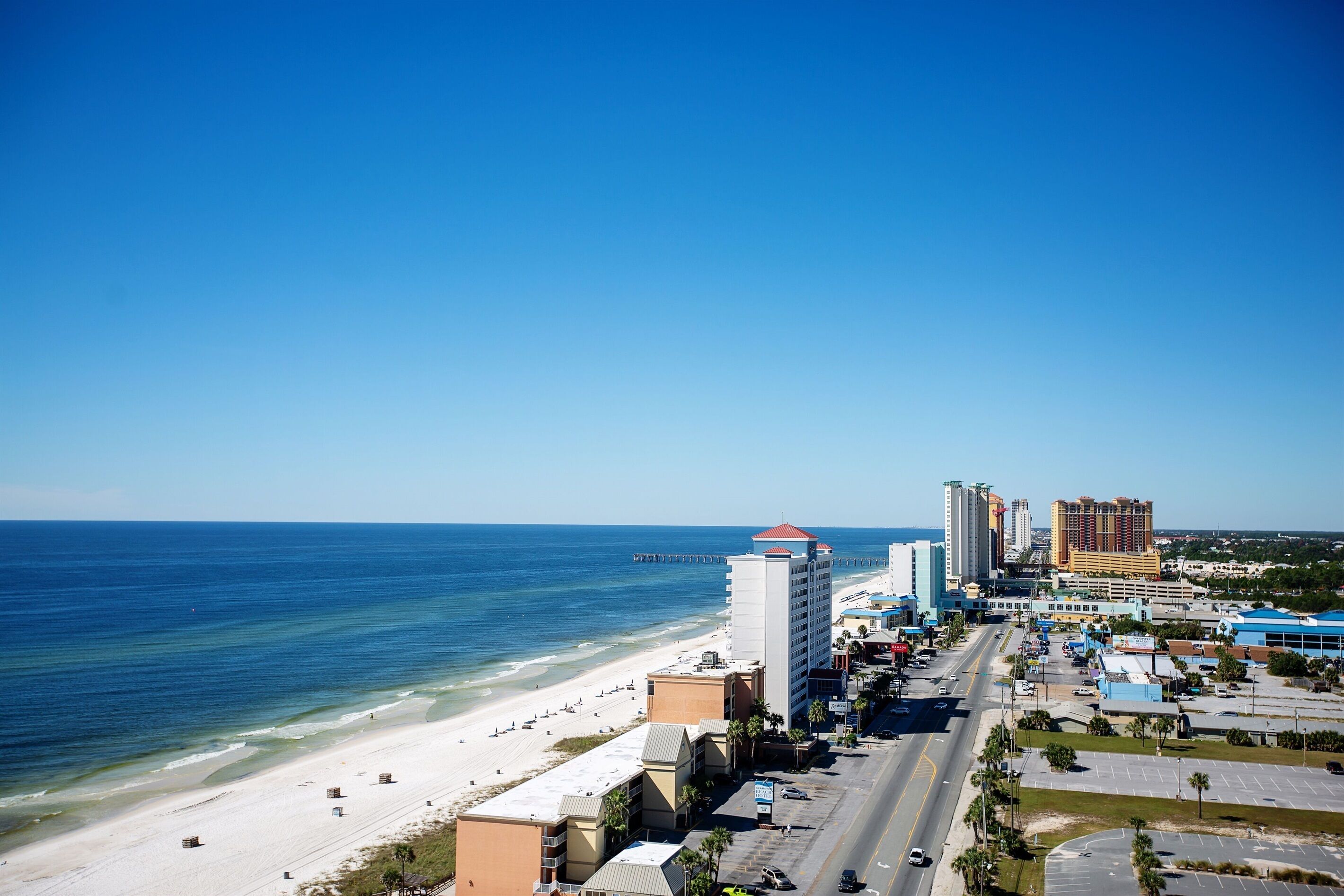A coastal cityscape with a beach, high-rise buildings, and a clear blue sky.