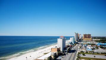 A coastal cityscape with a beach, high-rise buildings, and a clear blue sky.