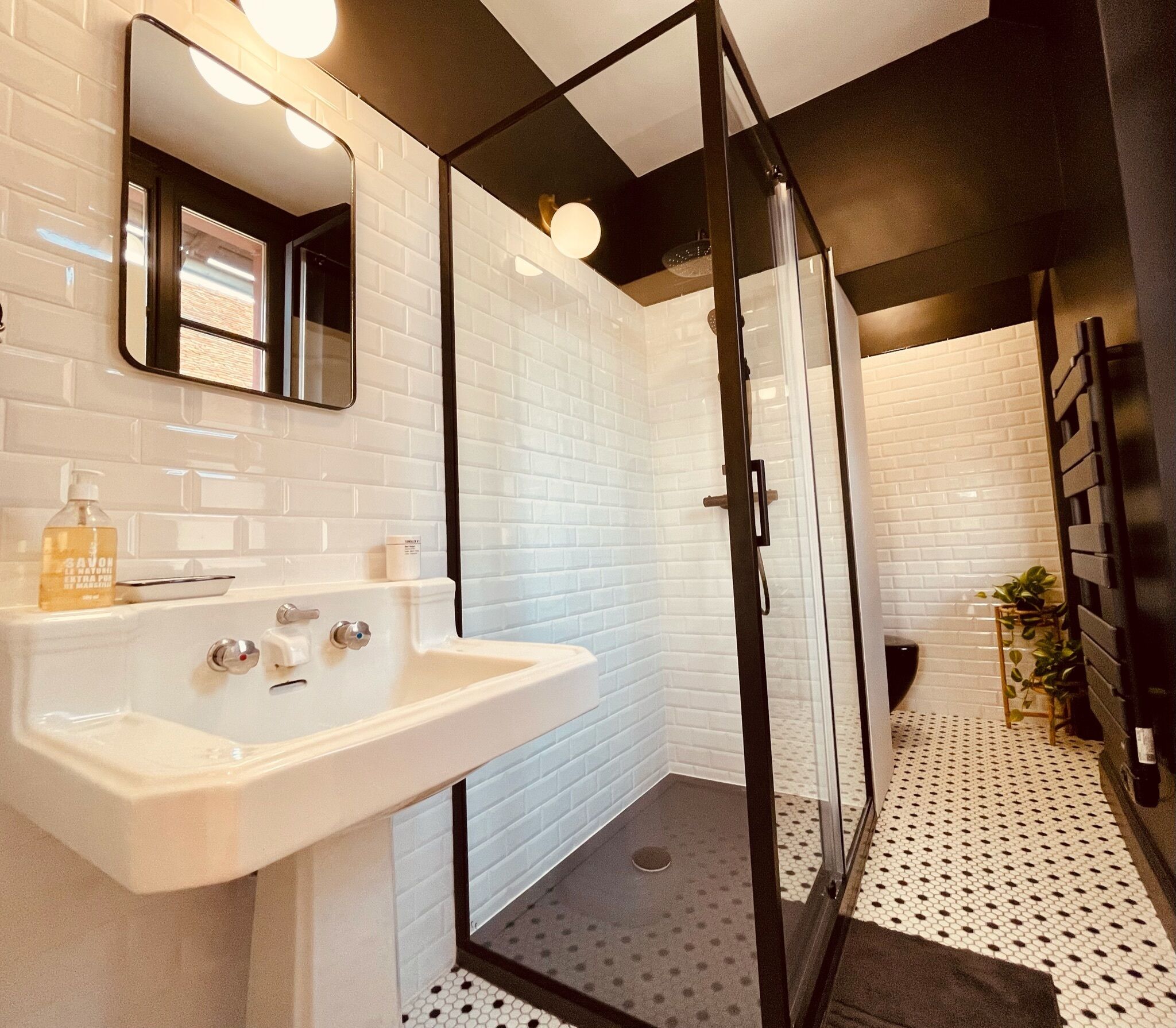 A modern bathroom with a white sink, mirror, and glass shower enclosure.
