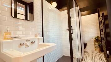 A modern bathroom with a white sink, mirror, and glass shower enclosure.