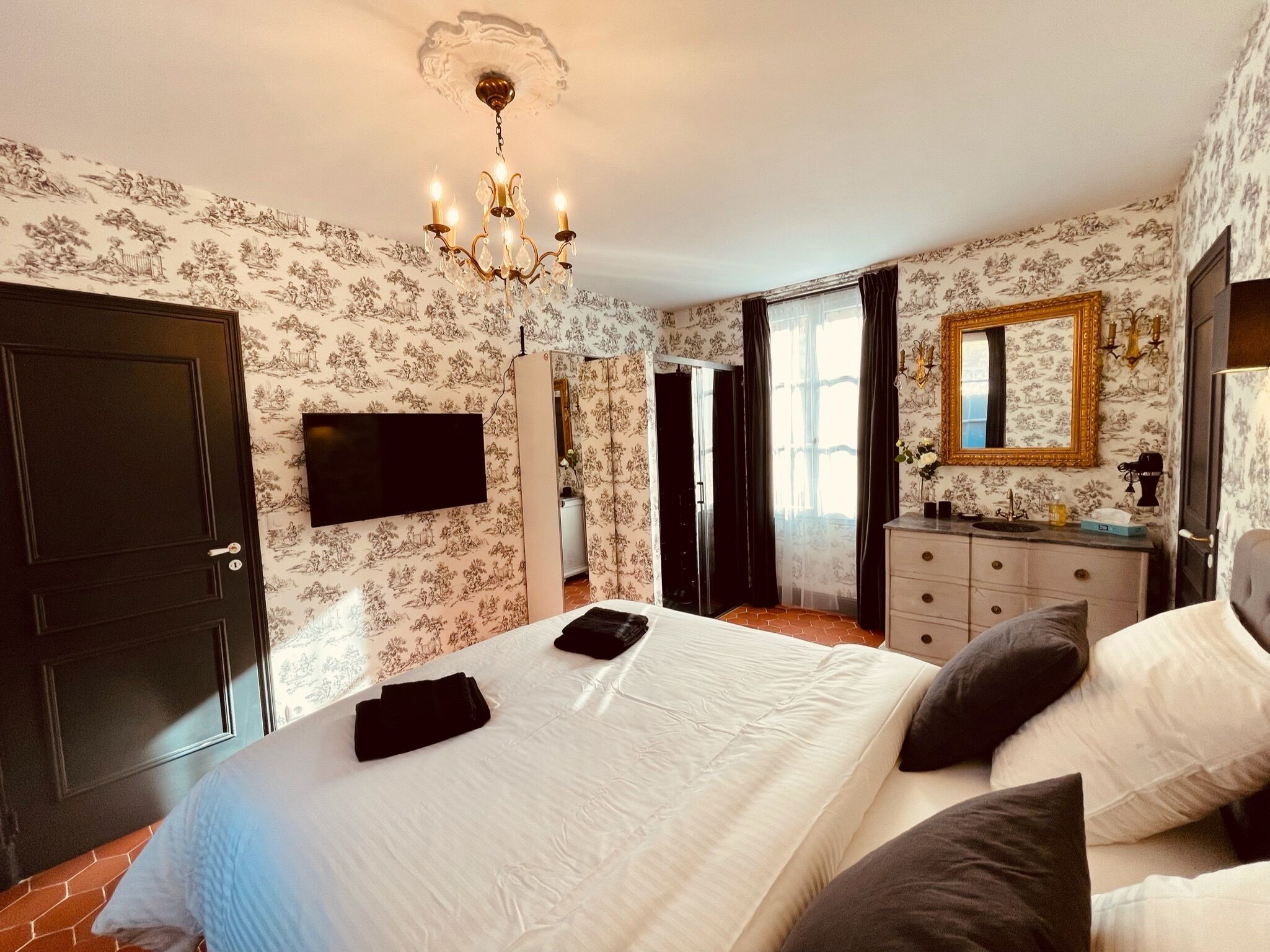 Un dormitorio con cama, tocador, espejo y candelabro.