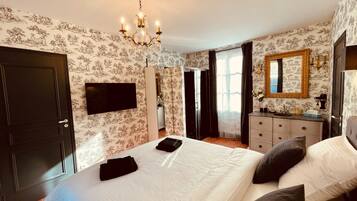 Un dormitorio con cama, tocador, espejo y candelabro.