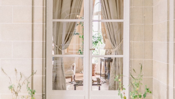Un arco blanco con un panel de vidrio, flanqueado por dos urnas blancas con plantas.