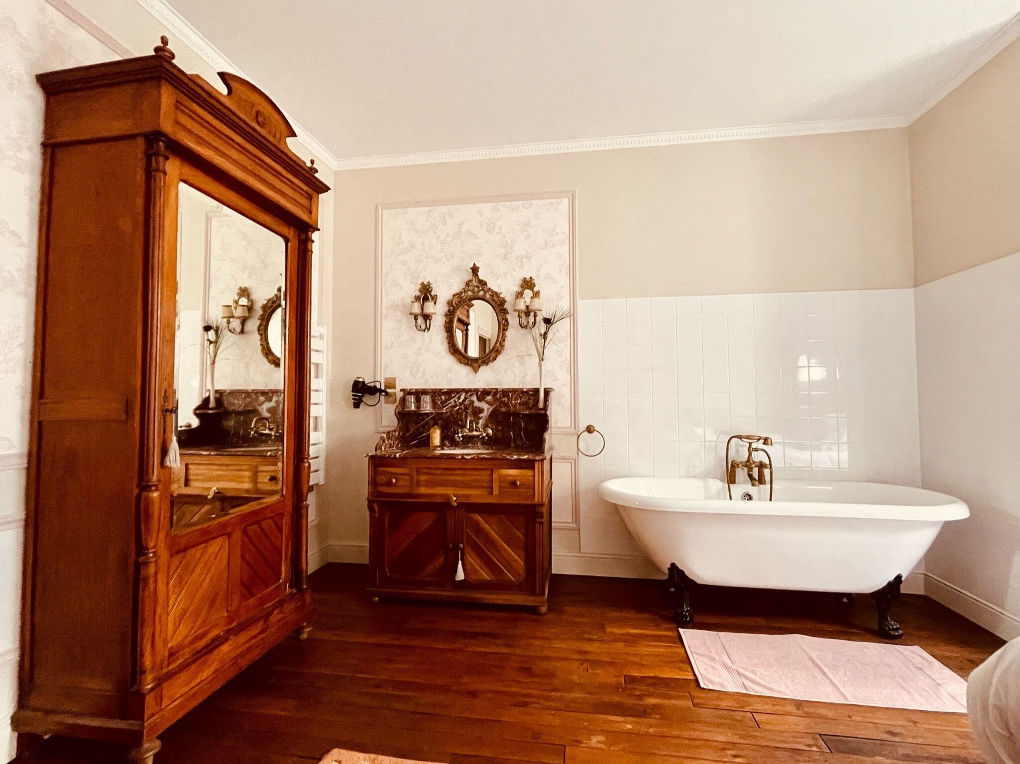 A classic bathroom with a wooden vanity, a freestanding bathtub, and a large mirror.