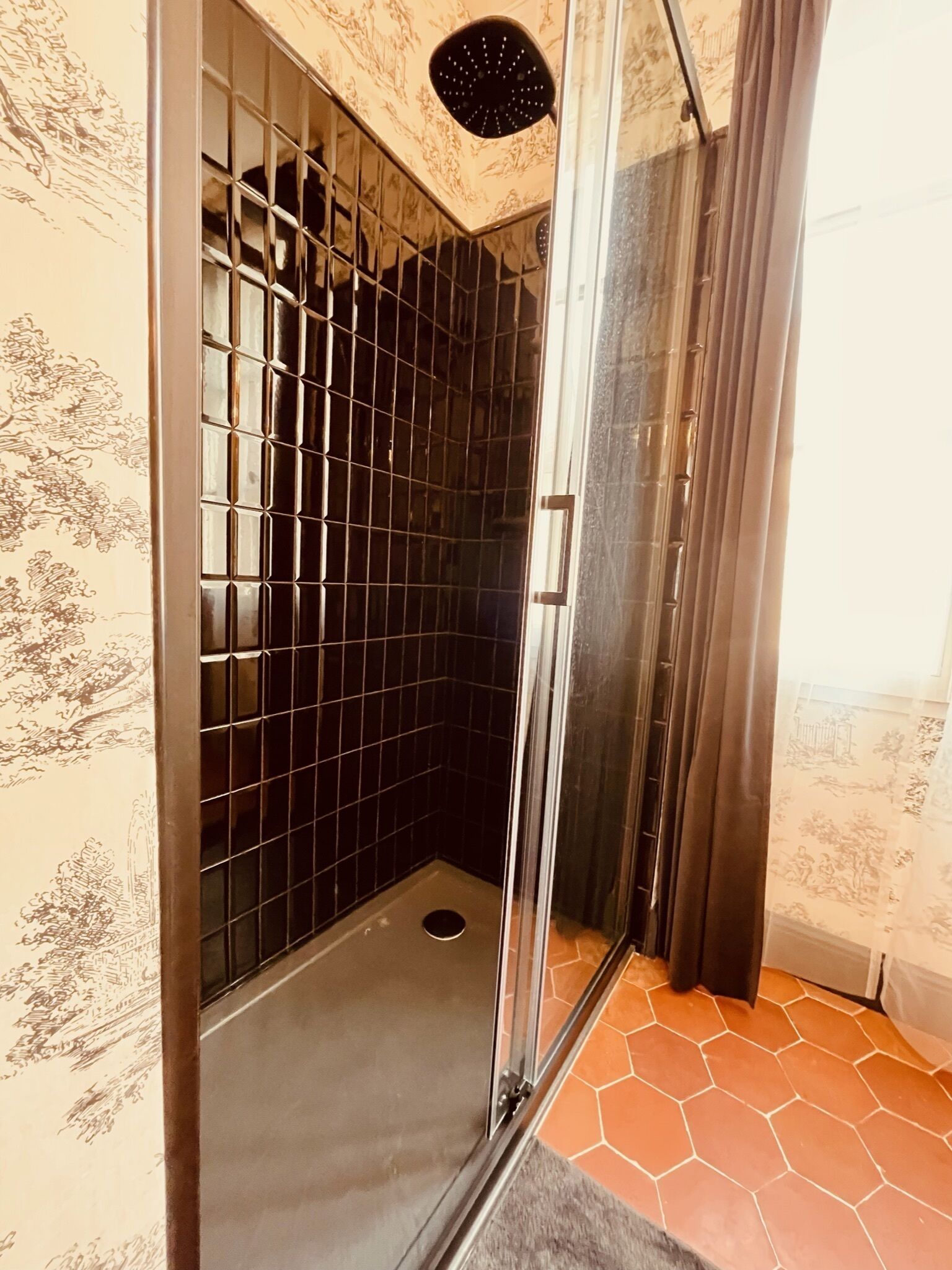 Eine Dusche mit Glastür, gefliesten Wänden und einem Musterfliesenboden.