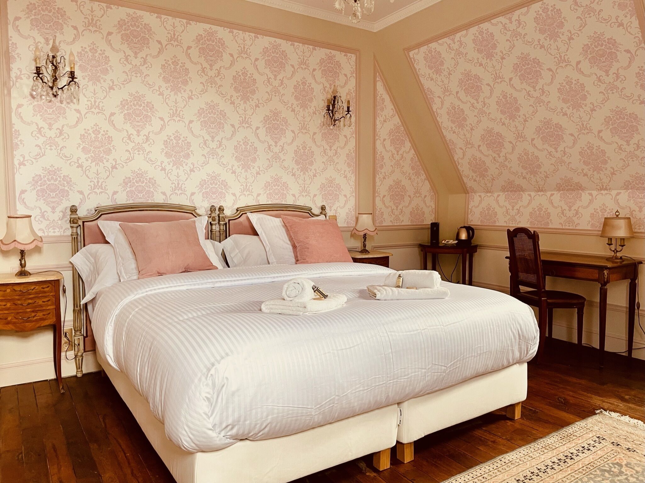 Ein Schlafzimmer mit einem großen Bett, zwei Nachttischen, einem Schreibtisch und einem Sessel.