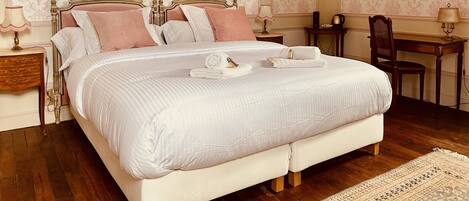 A bedroom with a large bed, two bedside tables, a desk, and a chair.