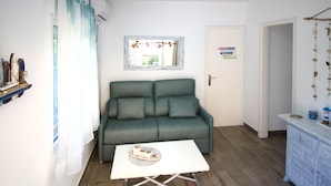 Un salon avec un canapé vert, une table basse blanche et un petit objet décoratif posé dessus.
