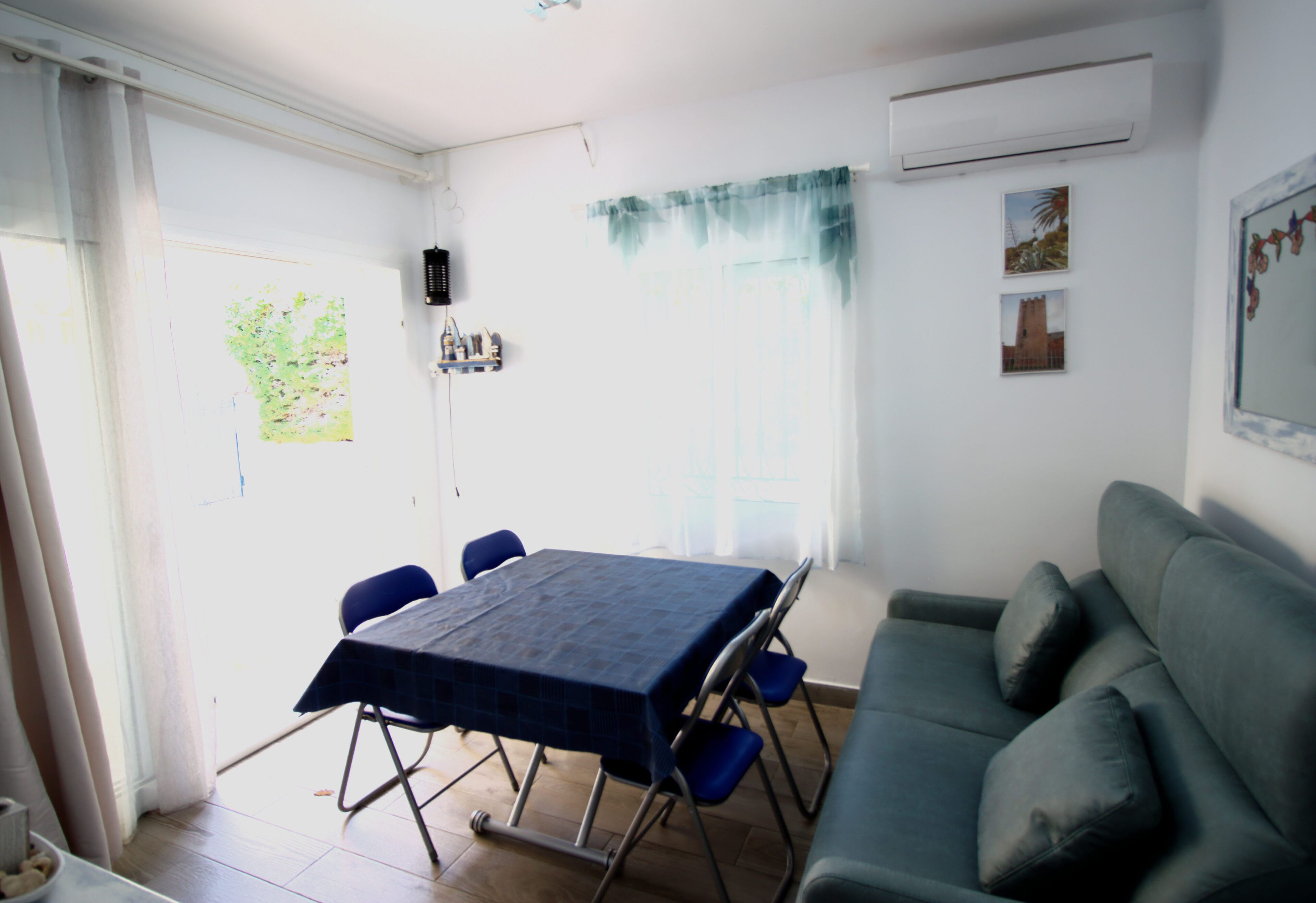 Ein Essbereich mit Tisch, Stühlen, einer Couch und einem Fenster mit Vorhängen.