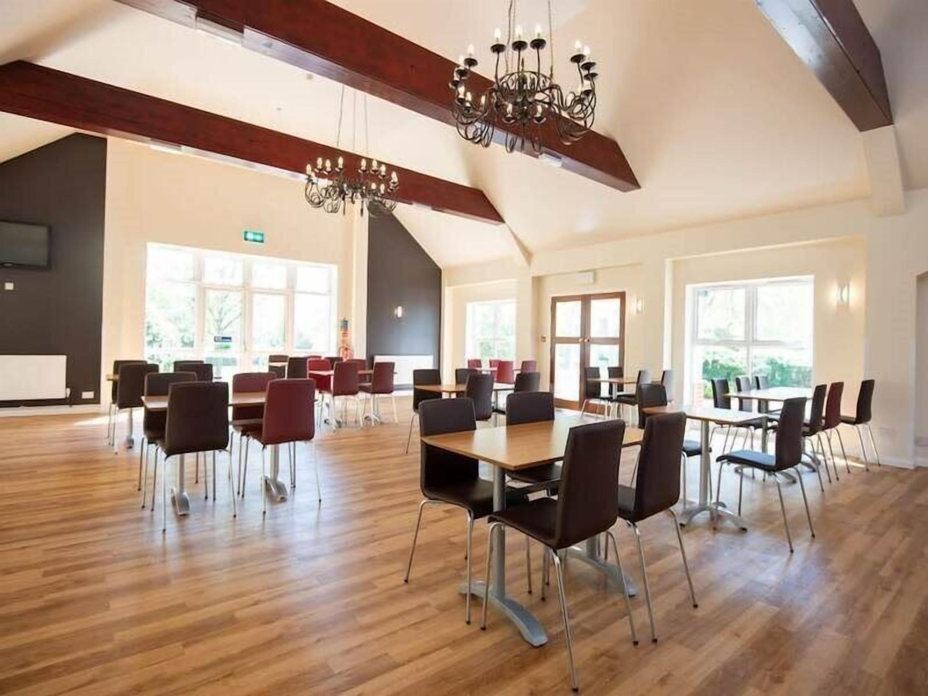 A spacious conference room with wooden floors, modern chairs, and a chandelier.