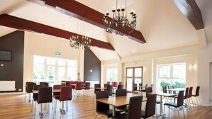 Una sala de conferències espaiosa amb terres de fusta, cadires modernes i un candelabrum.
