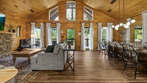 Uma cabana de madeira espaçosa com área de refeições, um sofá e uma lareira de pedra.