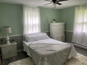 A bedroom with a bed, nightstand, dresser, and a ceiling fan.