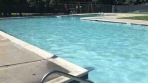 Une piscine aux eaux cristallines, bordée de carreaux, avec une zone herbeuse en arrière-plan.