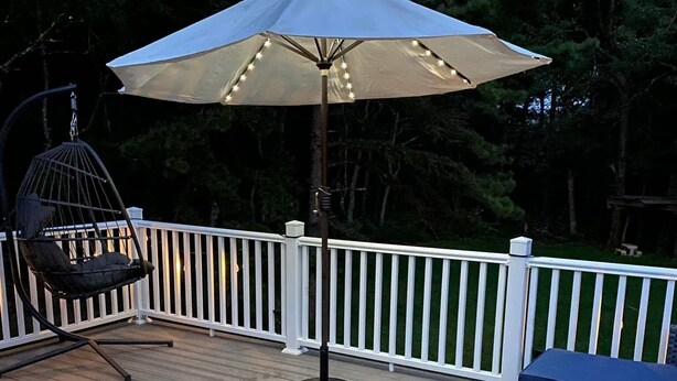 Une terrasse agrémentée d’un tapis à motifs, d’un fauteuil suspendu et d’un parasol.