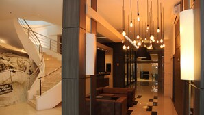 A modern lobby with a staircase, a seating area, and hanging lights.