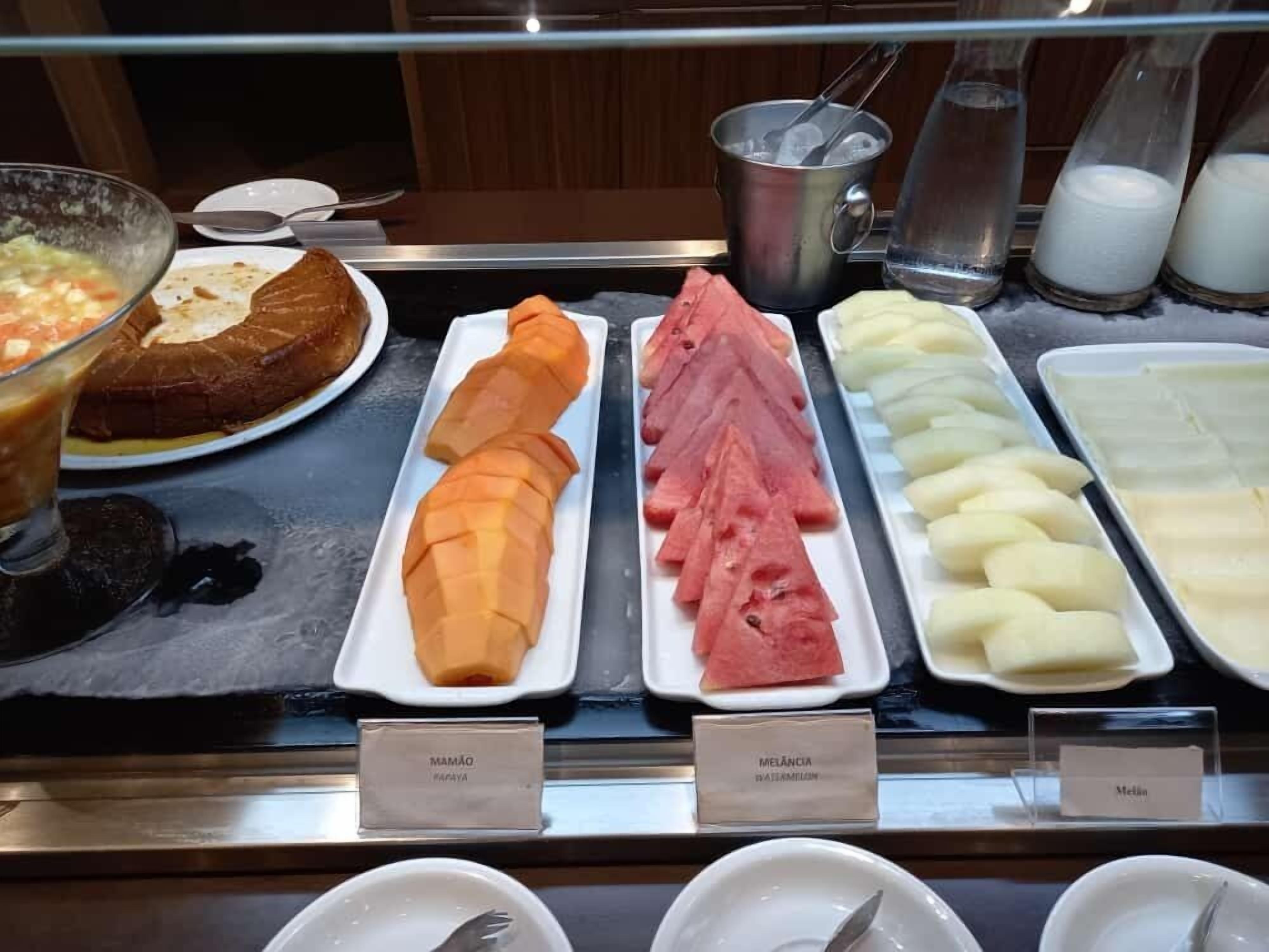 A breakfast buffet with various fruits and a hot beverage.