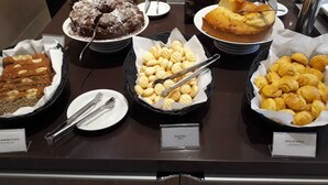 A buffet with various baked goods including banana bread, biscuits, and corn bread.