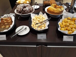 A buffet with various baked goods including banana bread, biscuits, and corn bread.