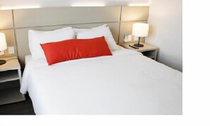 A hotel room with a bed, white bedding, a red accent pillow, and bedside lamps. - Samba Três Rios (Tres Rios)
