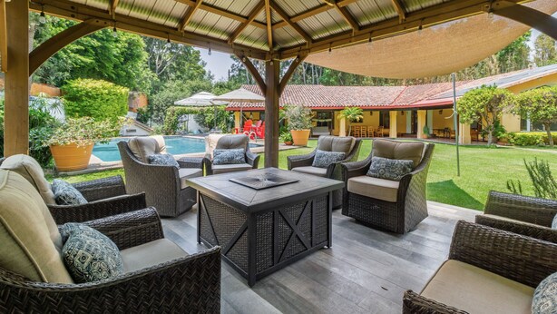 A covered outdoor seating area with wicker furniture and a pool in the background. - Amazing home for 10 people. "La Casa del Laurel" (Tepoztlán)