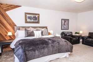 A bedroom with a bed, two bedside tables, a chair, a lamp, and two framed pictures on the wall. - Comfy house: 3 king beds, hot tub, attached garage (Red Lodge)