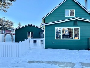 A two-story house with a white picket fence and a snow-covered yard.