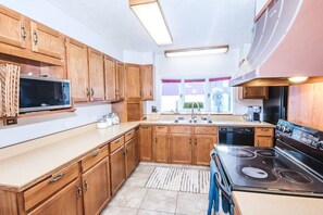 Une cuisine avec des meubles de rangement en bois, un four à micro-ondes, une cuisinière et un évier.