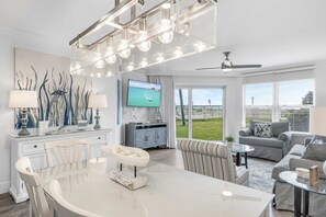 Relax in this stylish living room with a central island, flat-screen TV, and large window offering a view of a grassy area.