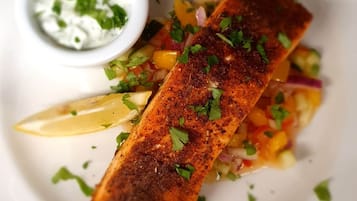 Une assiette contenant un morceau de poisson pané, une portion de légumes marinés et un petit bol de sauce.