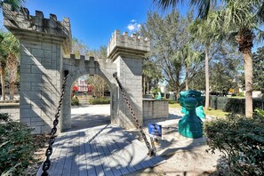 Une structure ressemblant à un château, dotée d’une grille fermée par une chaîne, d’un panneau indiquant un endroit idéal pour prendre des selfies et d’une grande sculpture verte.