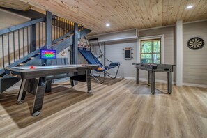 A room with a foosball table, a dartboard, and a pool table.