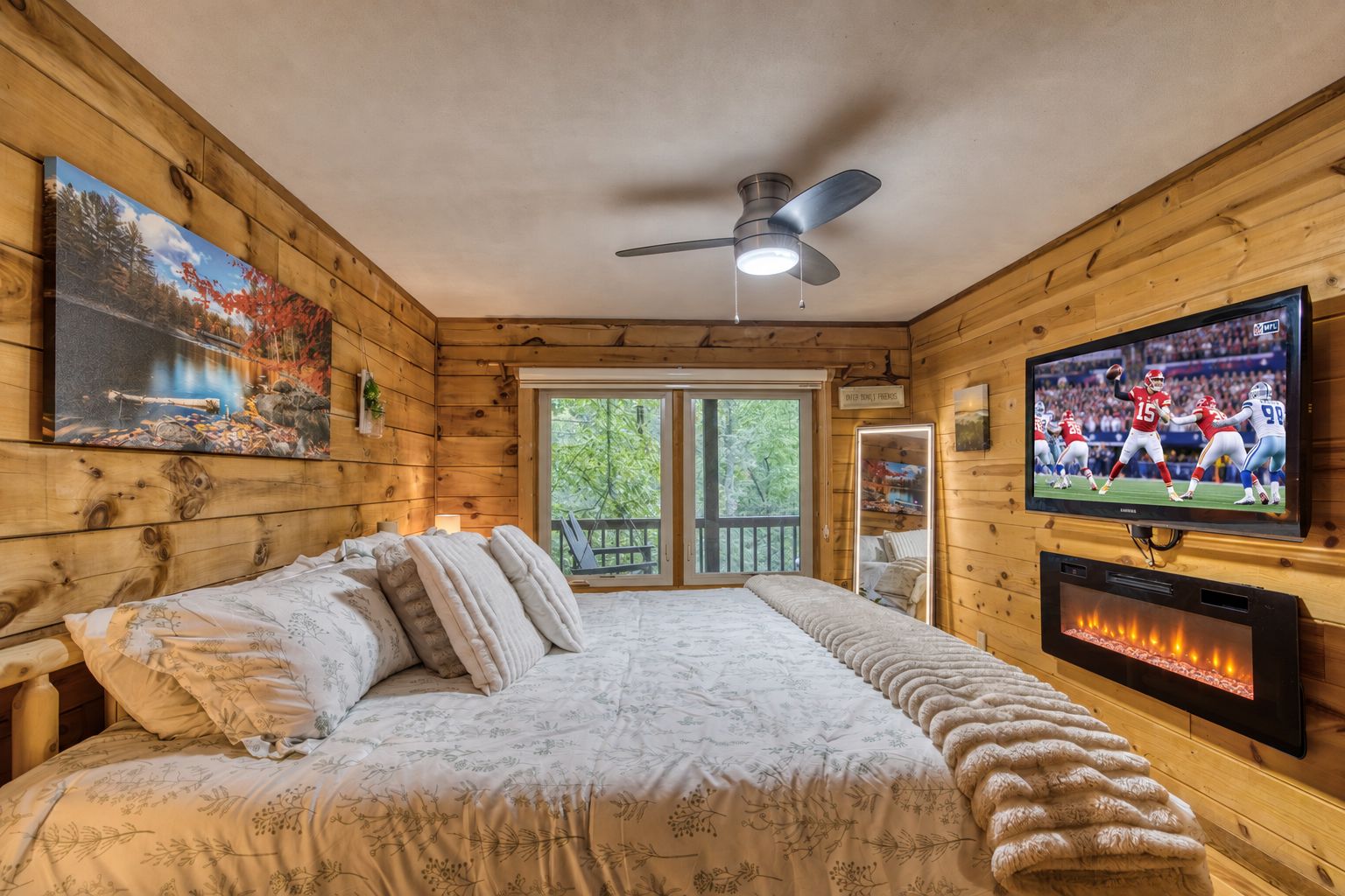 Ein Schlafzimmer mit einem Bett, einem Deckenventilator, einem Fernseher und einem Kamin.