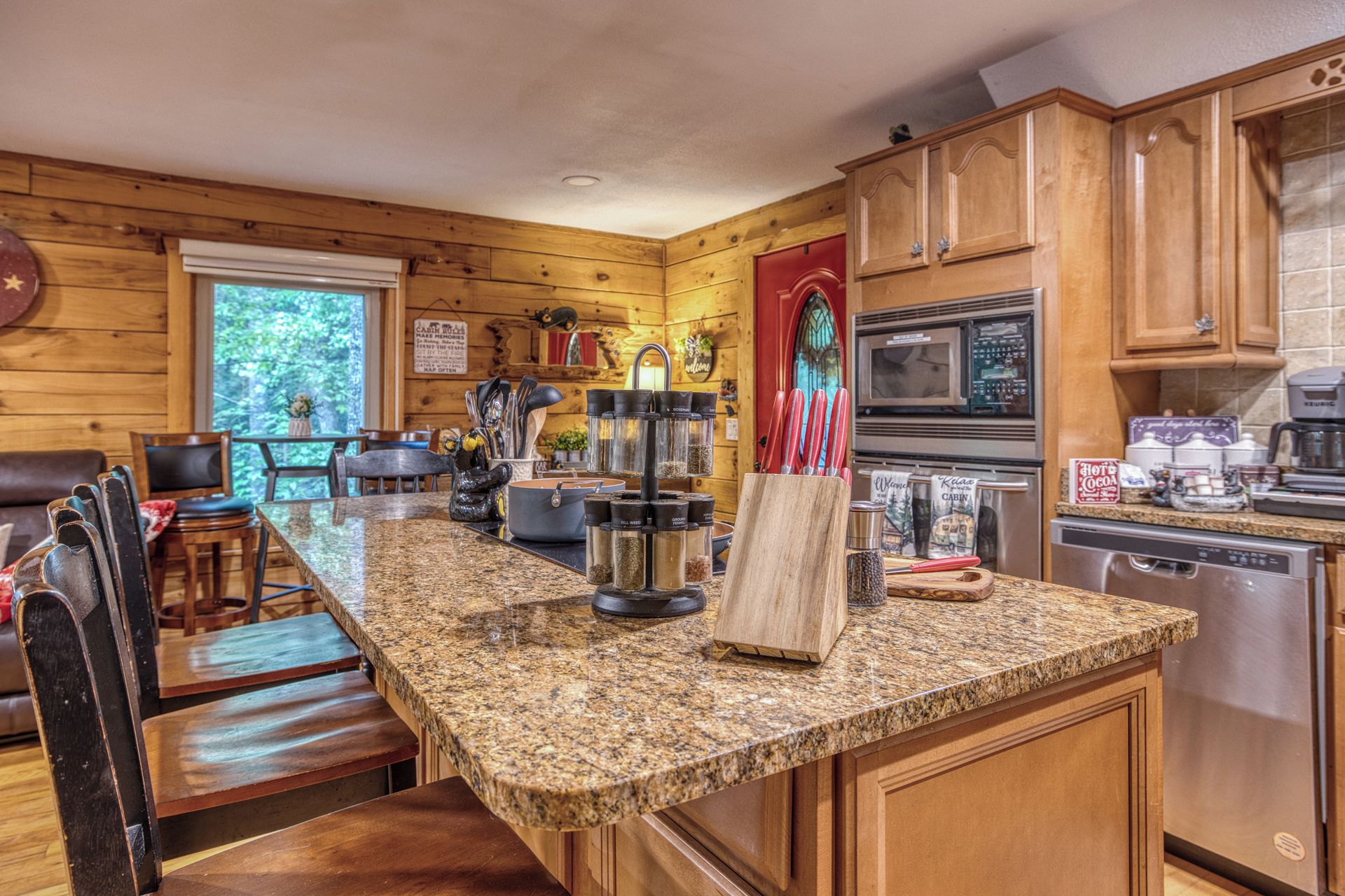 A kitchen with granite countertops, wooden cabinets, a stove, and a coffee maker.
