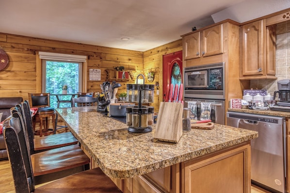 A kitchen with granite countertops, wooden cabinets, a stove, and a coffee maker.