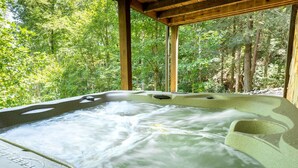 Ein Whirlpool in bewaldeter Landschaft, überdacht mit einer Holzhütte.