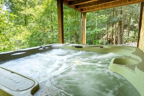 A hot tub in a forested area with a wooden structure overhead. - Bearfoot Bliss-Bear Hunt • Arcade • Hot Tub- Fire Pit- Adventure Cabin-Sleeps 12 (Blairsville)