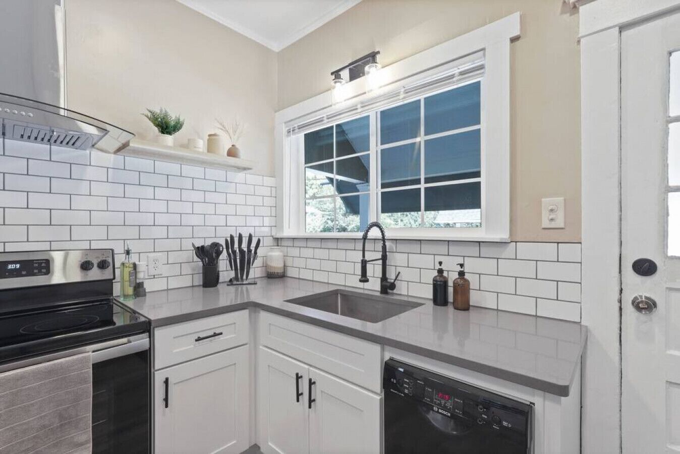 Una cocina moderna con armarios blancos, un lavavajillas Bosch y una ventana sobre el fregadero.