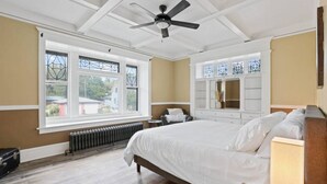 A bedroom with a large bed, a ceiling fan, a dresser, and a window with a view of the outside. - Cozy Home Overlooking Manito Park + Free parking! (Spokane)