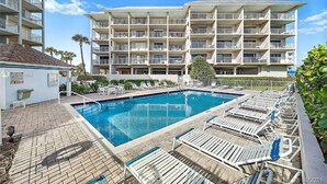 Un hôtel doté d’une piscine, de plusieurs balcons et d’un chemin en briques.