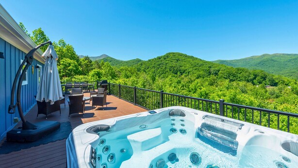 A hot tub on a deck with a view of green hills. - Heated Private Saltwater Pool; Hot Tub; 15 min AVL; 10 min Blue Ridge Parkway (Candler)
