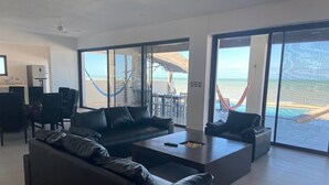 A spacious living area with a large sofa, a coffee table, and a view of the beach through large sliding glass doors. - Casa A LA Orilla DEL MAR CON Piscina (Telchac Puerto)