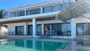 A modern building with a pool area, including a glass-enclosed patio and outdoor seating. - Casa A LA Orilla DEL MAR CON Piscina (Telchac Puerto)